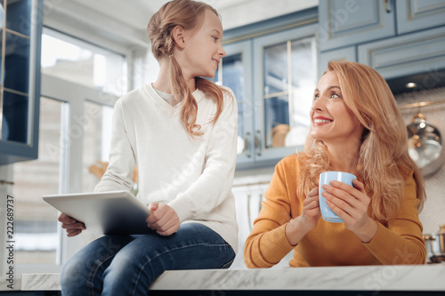 Lets discuss it. Cheerful blonde woman keeping smile on face and enjoying her talk with daughter