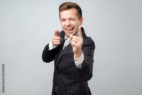 Portrait of handsome young smiling man pointing fingers at camera, picking you as winner photo