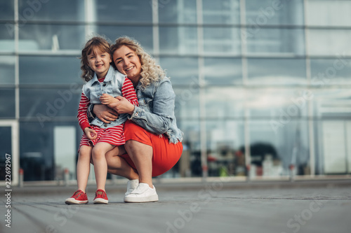 Beautiful Young Mother with Small Stylish Daughter Walks Through City Together