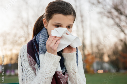 Photos Sick woman blowing her nose in the park during autumn