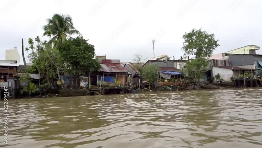 Boat driving past houses on the mekong delta Boat driving past houses on the mekong delta