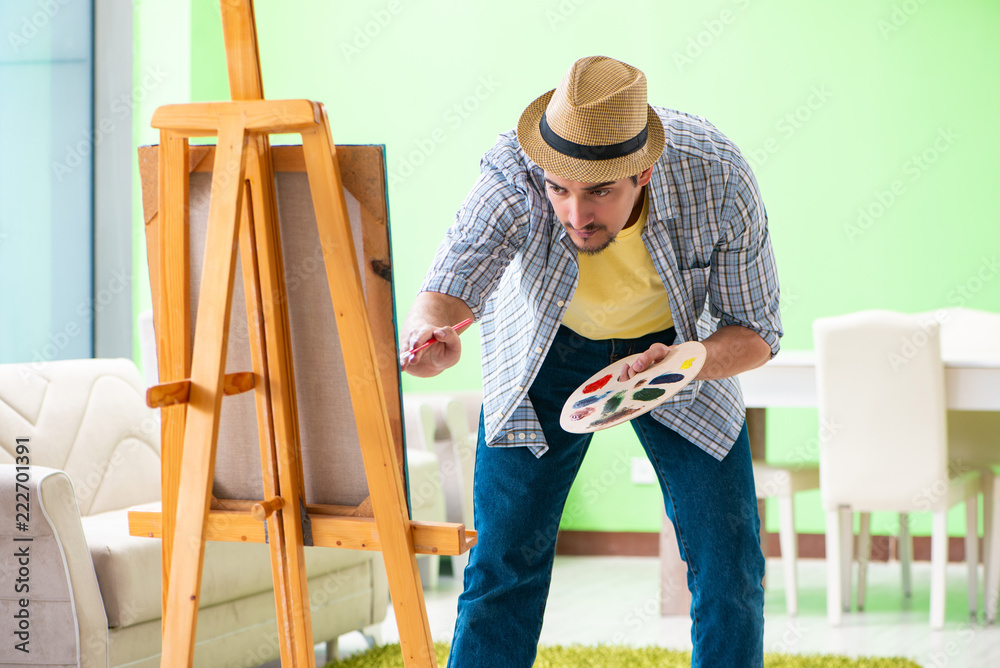 Young male artist working on new painting in his studio Young male artist working on new painting in his studio