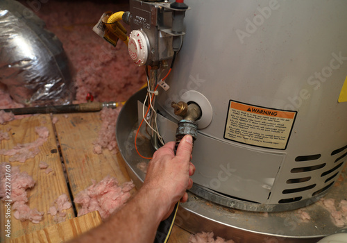 Hand attaches hose to drain water heater