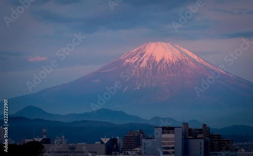 Morning light illuminating the peak of mount Fuji in the background of a small city