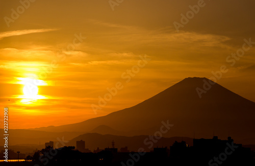 A golden sun setting beside the silhouette of mount Fuji