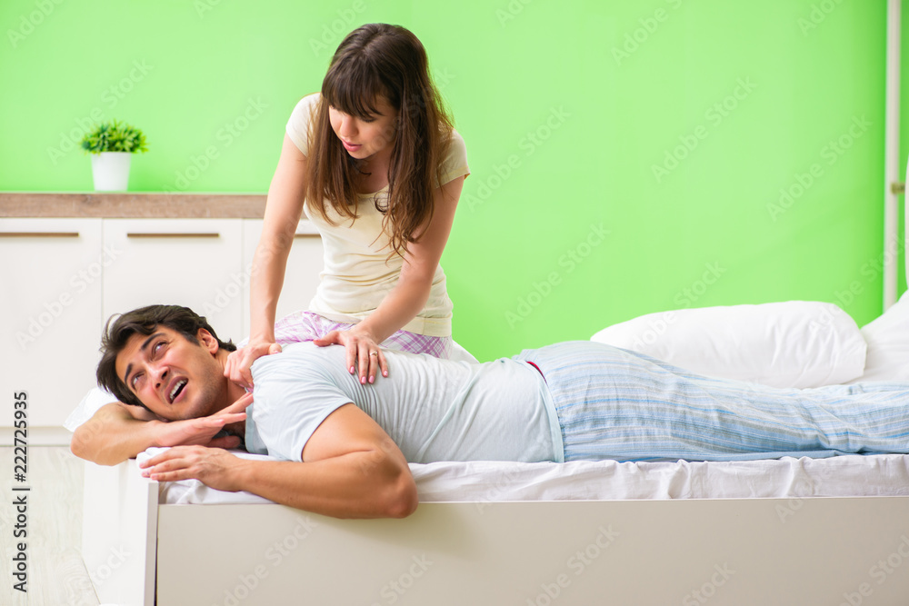 Woman doing massage to her husband in bedroom Woman doing massage to her husband in bedroom
