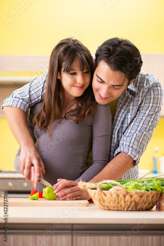Man and pregnant woman preparing salad in kitchen 