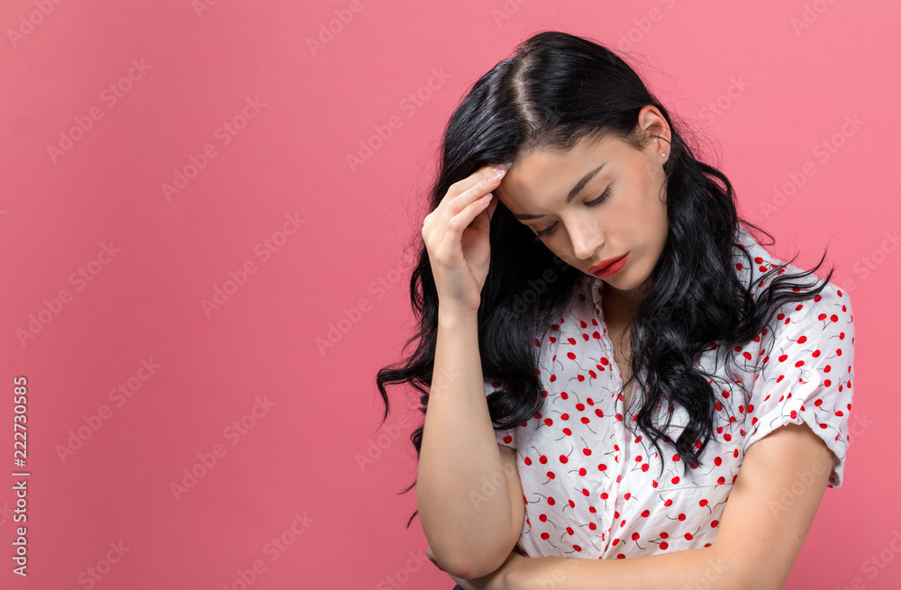 Young woman suffering from headache on a solid background