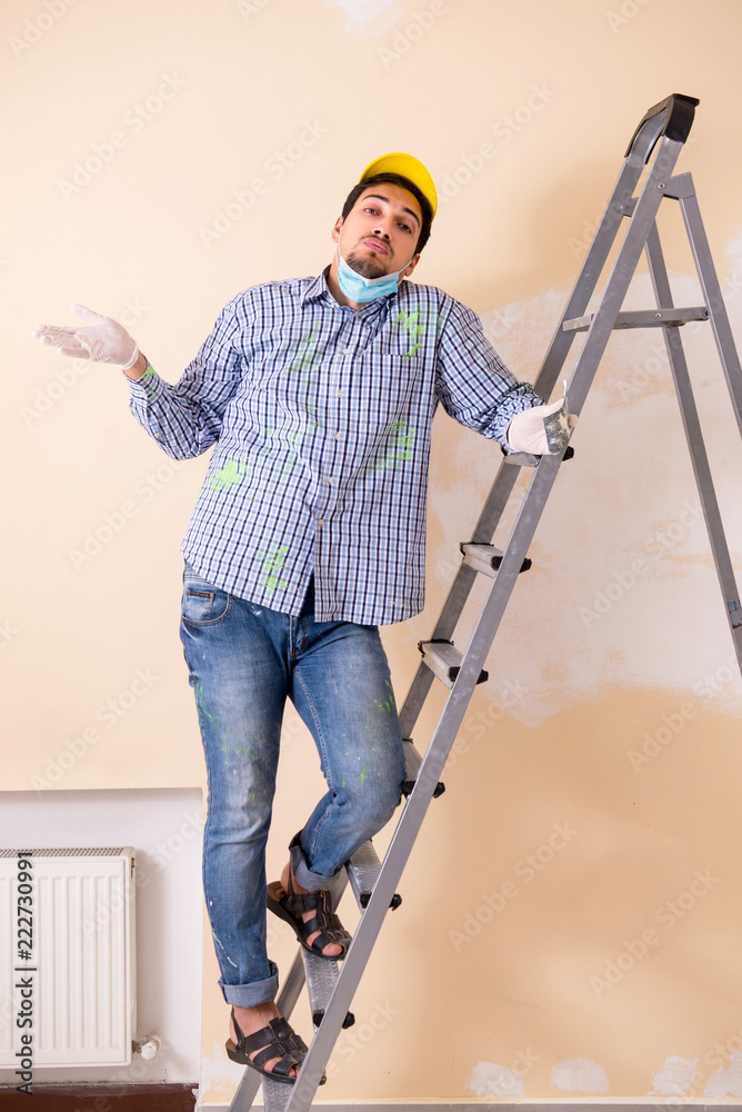 Young contractor sanding wall down with sandpaper Young contractor sanding wall down with sandpaper