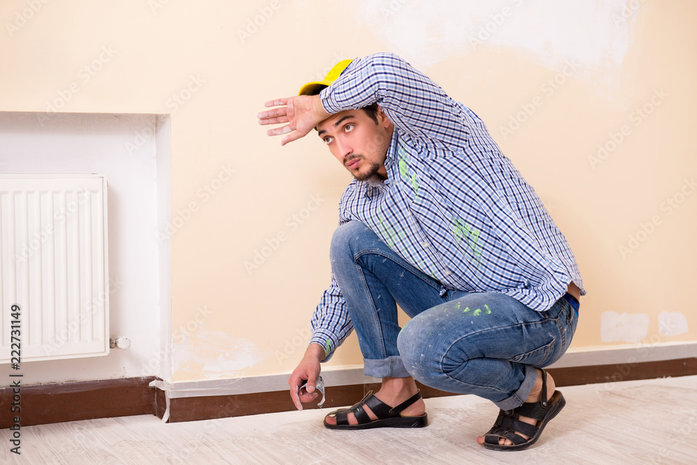 Young contractor sanding wall down with sandpaper Young contractor sanding wall down with sandpaper