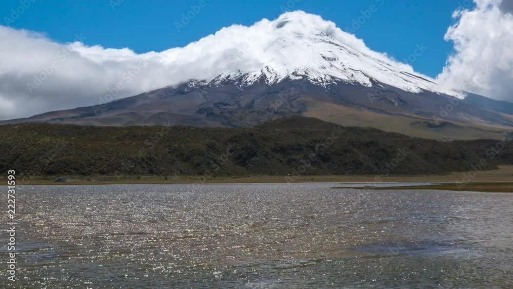 Cotopaxi Volcano, Ecuador, reflected in a lake. Time-lapse. On a windy day with clouds blowing over the mountain and vapour coming out of the crater. Laguna Limpiopungo in foreground. Cotopaxi Volcano, Ecuador, reflected in a lake. Time-lapse. On a windy day with clouds blowing over the mountain and vapour coming out of the crater. Laguna Limpiopungo in foreground.