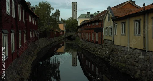 Tilting shot of the canal in central Västerås, with historic red houses on boths sides.