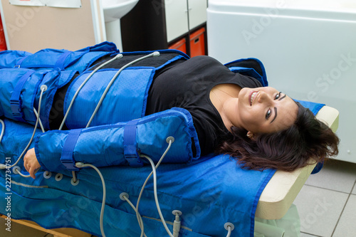 Woman having procedure of anti cellulite massage on pressotherapy machine photo