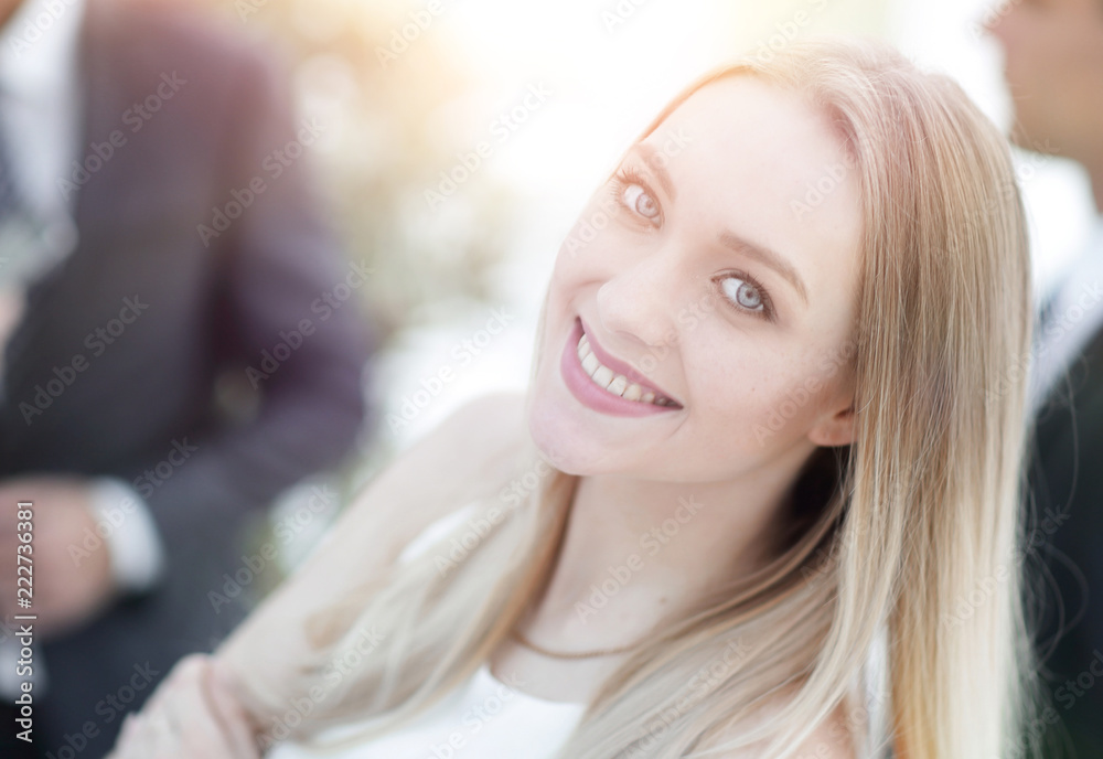 close-up of a young woman in the office on the background of colleagues. close-up of a young woman in the office on the background of colleagues.