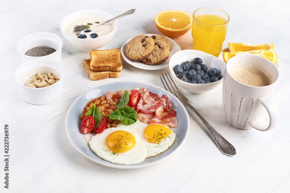 Breakfast with fried eggs, bacon, orange juice, yogurt and toasts Breakfast with fried eggs, bacon, orange juice, yogurt and toasts