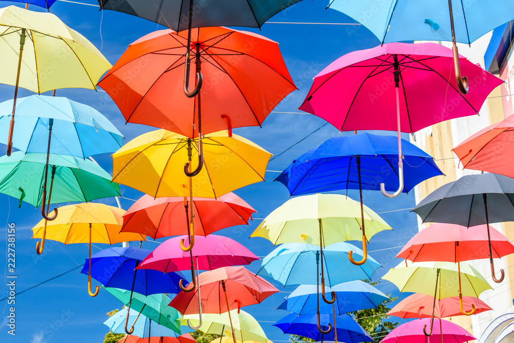 Different colorful umbrellas hanging over the street against sky Different colorful umbrellas hanging over the street against sky