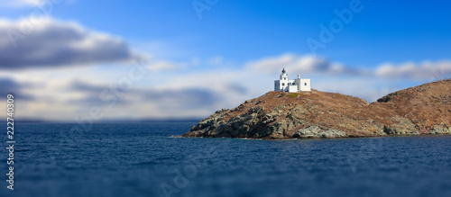 Fototapeta Naklejka Na Ścianę i Meble -  Lighthouse and agios Nikolaos church. Kea,Tzia island, Greece. Blur cloudy sky background, banner.