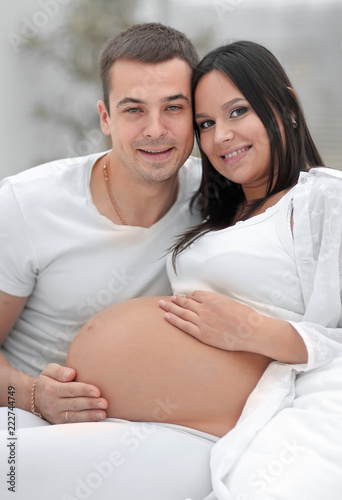 portrait of pregnant woman with husband sitting on the couch