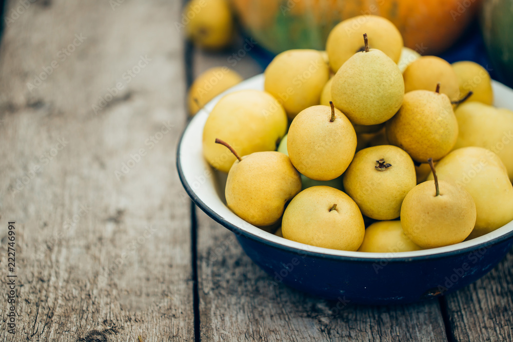 Beautiful ripe home pears in a large bowl on wooden background