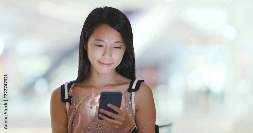 Woman use of mobile phone with shopping mall background