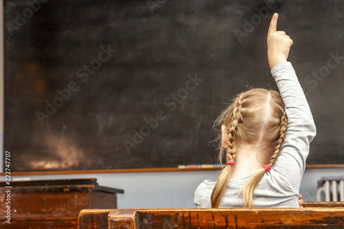 Fotografia Concept of public primary school education with young girl raising her hand in t