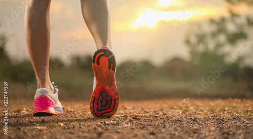 Runner feet running on rough road closeup on shoe. woman fitness sunrise jog concept...