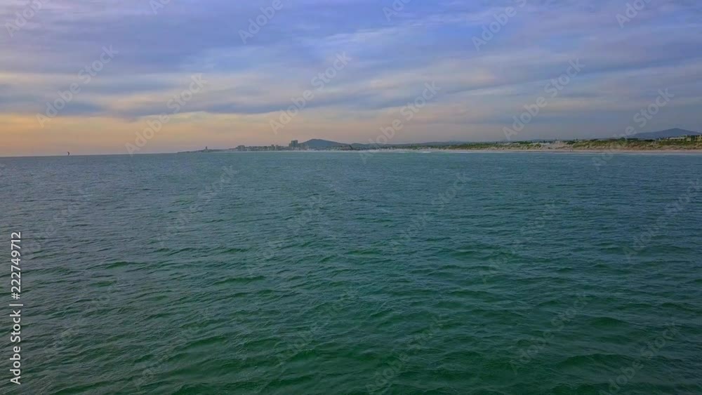 fly around vast ocean at sunset with ship in the distance