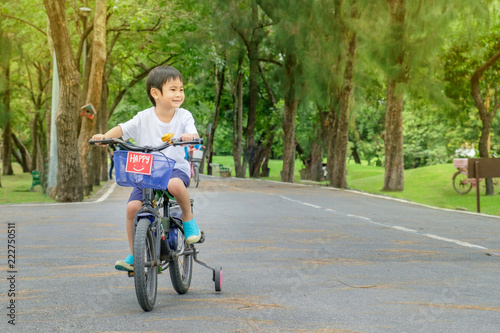 Fototapeta Naklejka Na Ścianę i Meble -  Asian cute boy ride a bicycle at park green nature background.Copy Space Image.