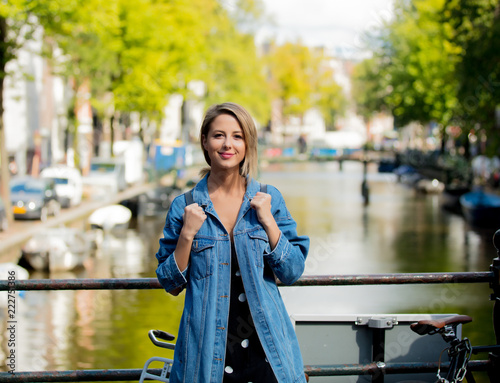 Canvas Print Young girl in jeans jacket and backpack at bridge in Amsterdam street
