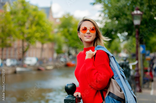 Photography Young girl in red sweater and orange sunglasses with backpack at bridge in Amsterdam street