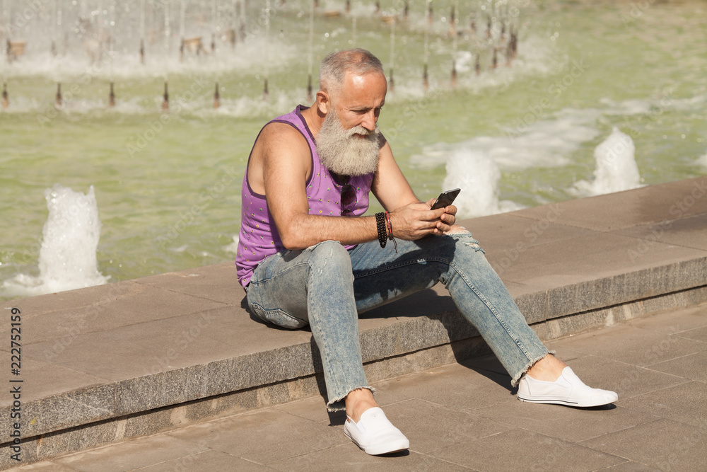 Trendy senior man using smartphone in downtown center outdoor - Mature fashion male having fun with new trends technology - Tech and joyful elderly lifestyle concept
