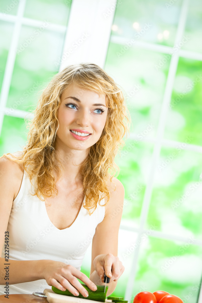 Young cheerful blond woman making salad