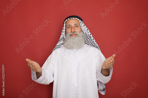 handsome muslim man presenting empty space isolated on red photo