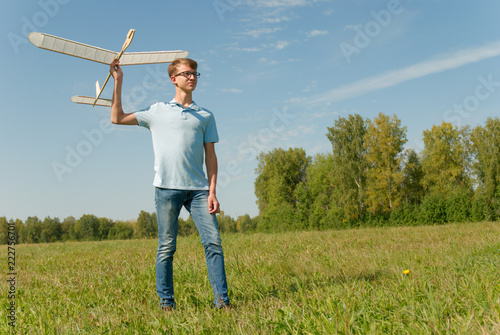 Hansome teenager  throwing DIY glider in the grass. Dream conception photo. © zergsv