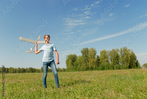 Hansome teenager throwing DIY glider in the grass. Dream conception photo.