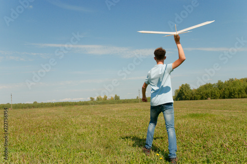 Hansome teenager  throwing DIY glider in the grass. Dream conception photo.