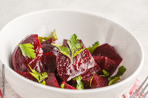 Baked beet salad with parsley and oil in a white bowl.