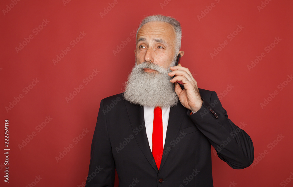 Bearded Senior Businessman in a formal suit on red background smartphone communication Bearded Senior Businessman in a formal suit on red background smartphone communication