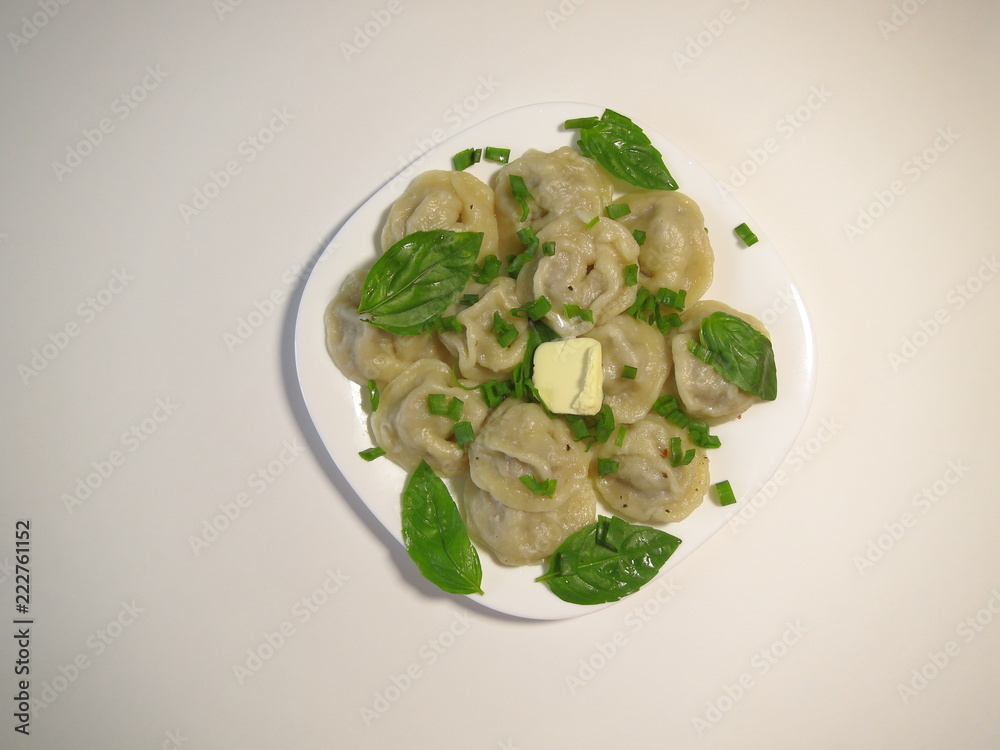 Boiled dumplings on a white background with Basil and a piece of butter. Boiled dumplings on a white background with Basil and a piece of butter.