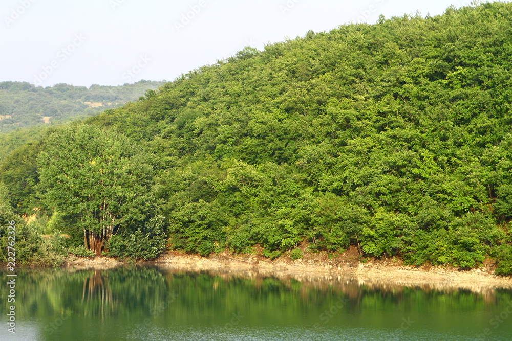 Fototapeta premium beautiful still lake with green hills in distance. natural landscape photo.