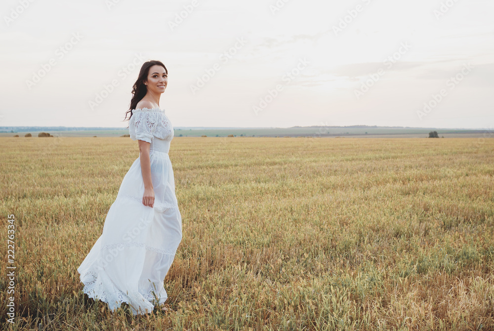 Beautiful young woman in the white dress on the field