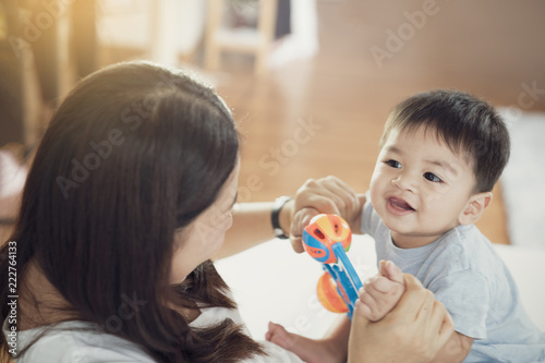 Happy loving family. Mother playing with her baby in the bedroom. Pretty woman holding a newborn baby in her arms  Mother with child playing educational toys 