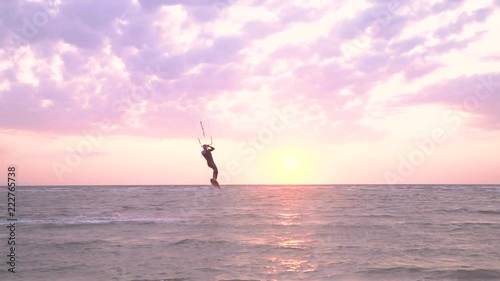 A man kitesur jumps into the air, lands on his feet and goes to shore