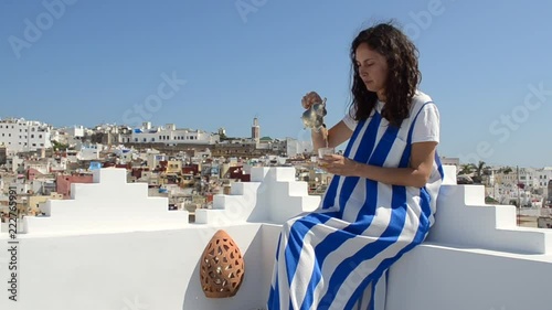 Woman serves the typical tea on a wonderful terrace overlooking the Moroccan city of Tangier. Amazing scene of life in Morocco