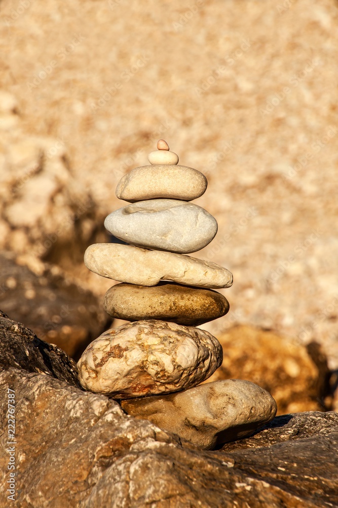 Pebble stack on the seashore. Pyramid of stones on the beach. Light at sunset. Symbol of patience. Concept of harmony and balance. Memory of the sea. Pebble stack on the seashore. Pyramid of stones on the beach. Light at sunset. Symbol of patience. Concept of harmony and balance. Memory of the sea.