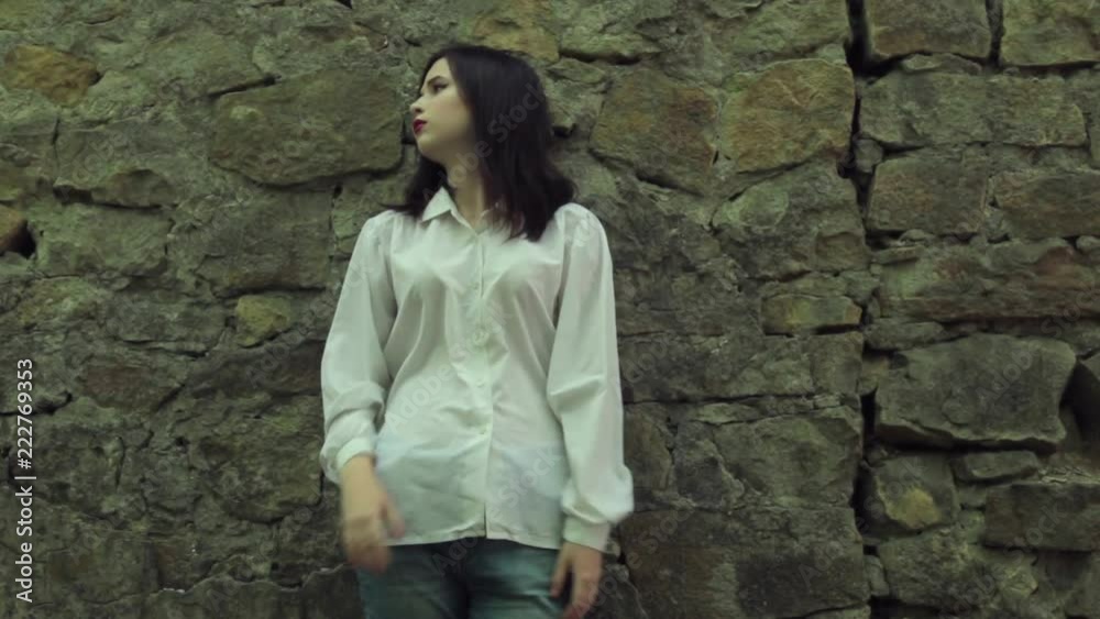 Beautiful brunette dreaming and sad, standing near a stone wall. Beautiful brunette dreaming and sad, standing near a stone wall.