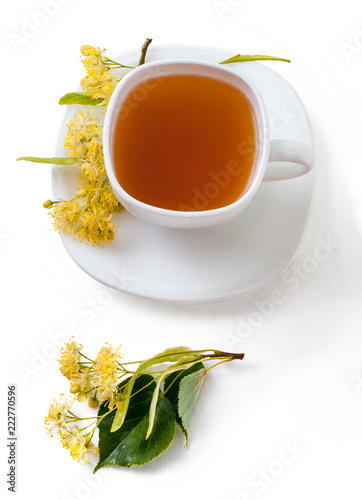 A cup with linden tea and flowers on white background. Top view, isolated