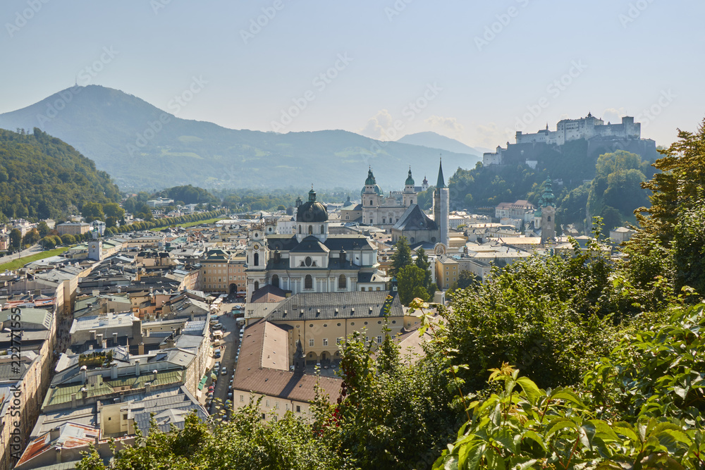 Obraz premium Landscape view of the city of Salzburg in Austria with a cathedral and a castle in the background.