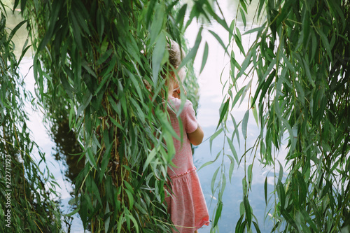 Fotografija little girl standing inside the branches of weeping willow
