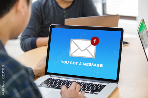 Man working on laptop and got a message from someone at modern office